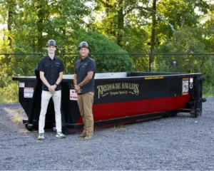 Firehouse Haulers employees standing in front of a Firehouse Haulers 12 Yard Dumpster.
