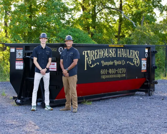 Firehouse Haulers employees standing in front of a Firehouse Haulers 20 Yard Dumpster.